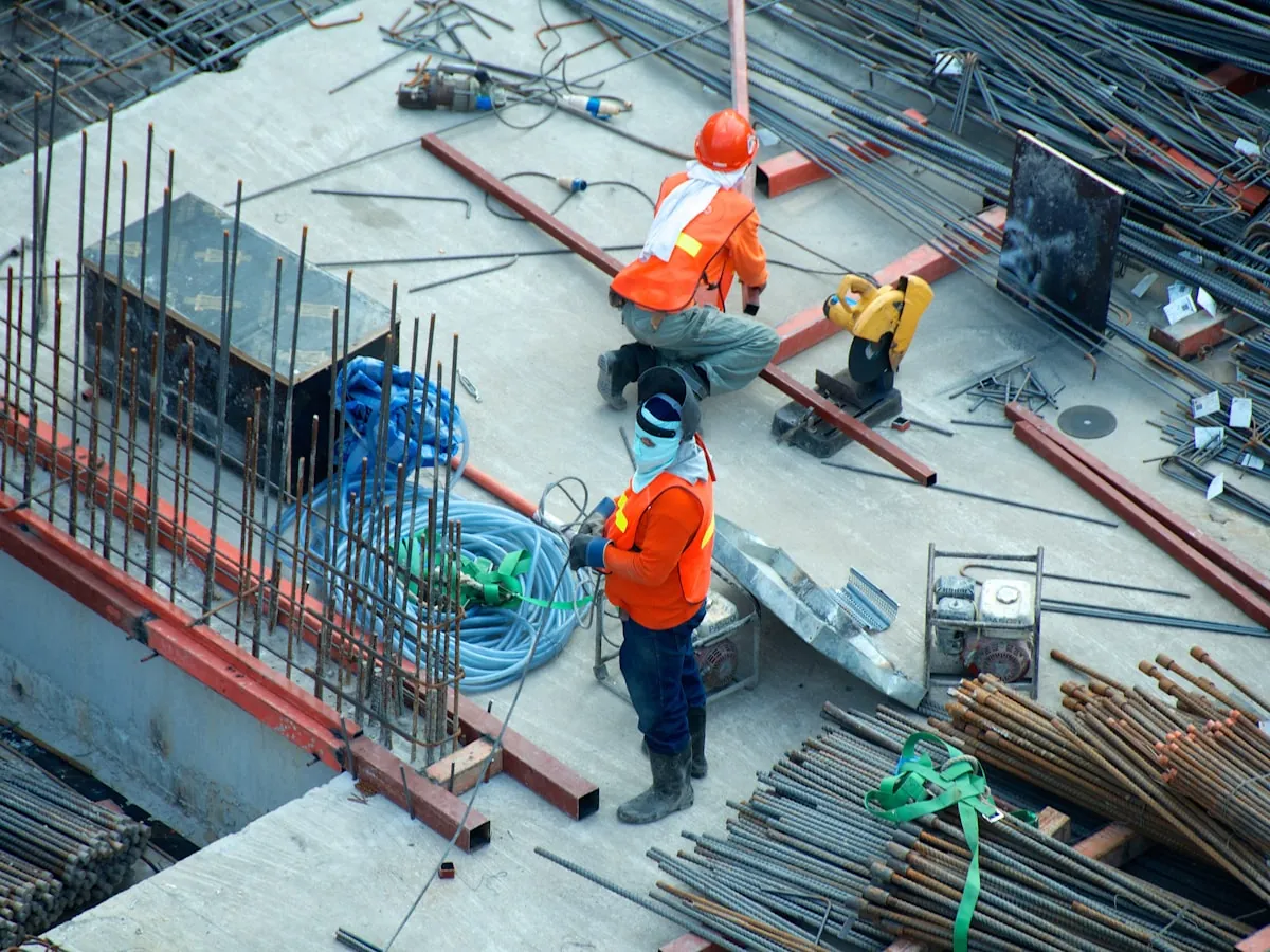 Ouvriers en gilet orange sur un chantier de gros œuvre, vus du dessus